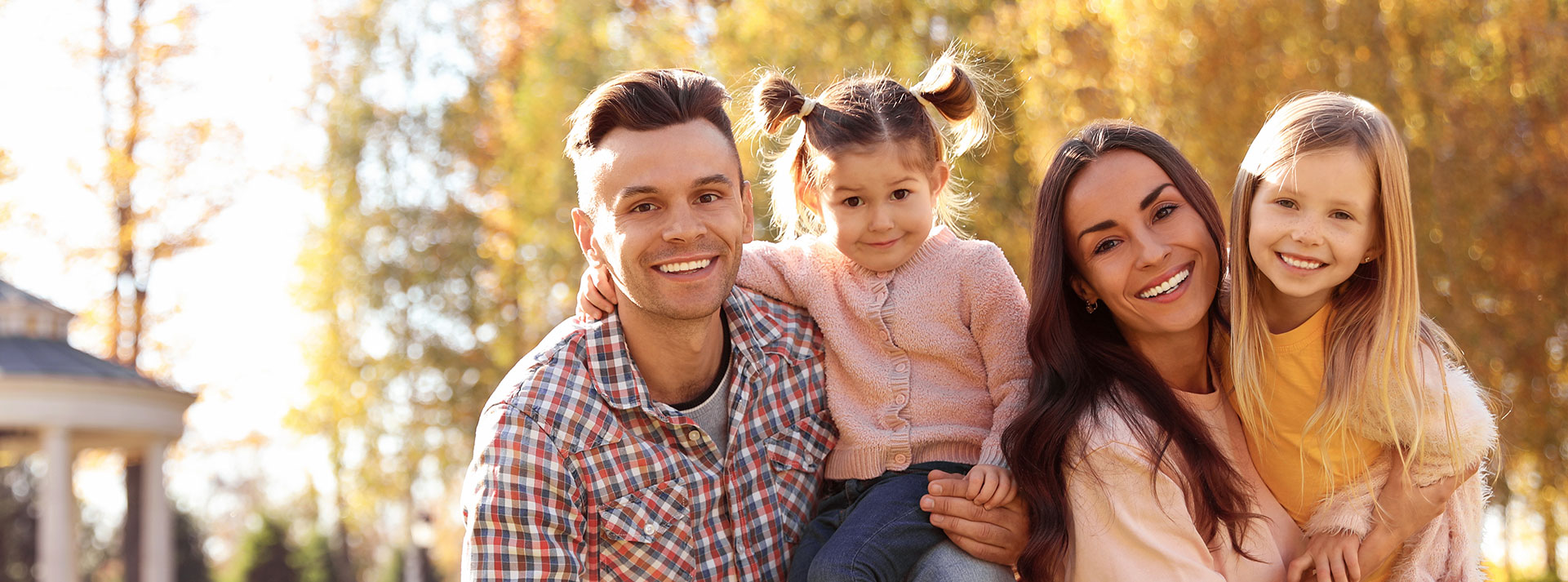 This is a photograph featuring a family with a man, woman, and children outdoors during autumn, with a smiling couple posing for the camera.