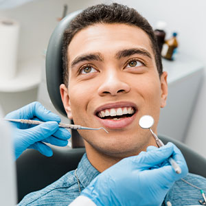 A man in a dental chair receiving treatment with a smile on his face.