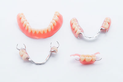 The image shows three sets of dentures with visible teeth on a plain background, displayed in a way that suggests they are for sale or display.