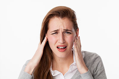 The image shows a woman with her hand on her head, possibly expressing disbelief or confusion, with a concerned facial expression.