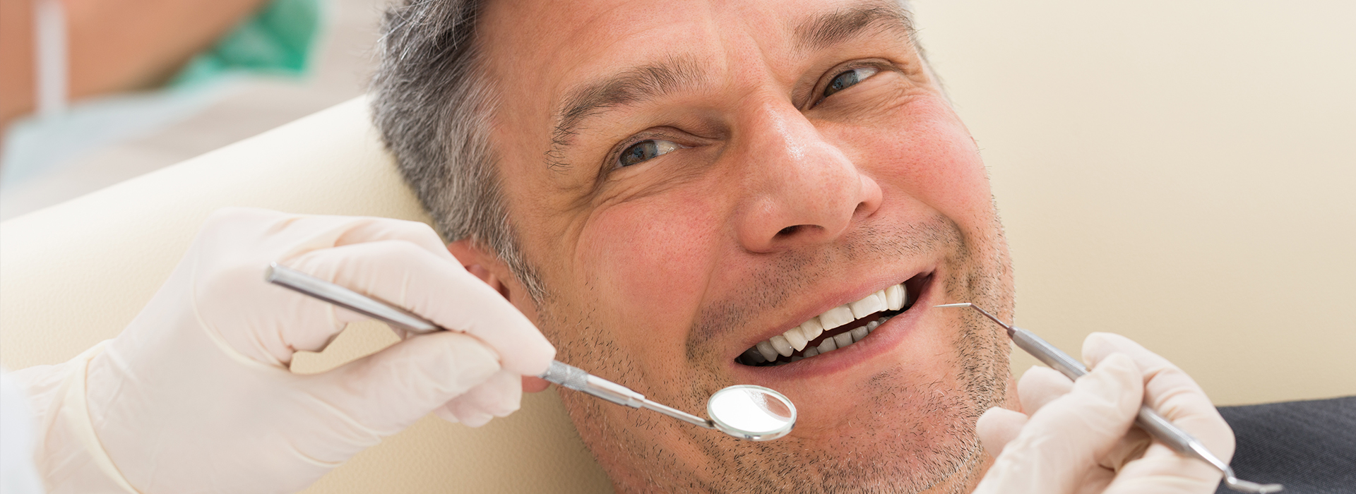 A man sitting in a dental chair receiving dental care, with a smiling expression.