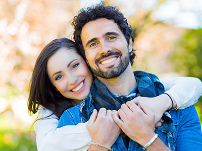 The image shows a man and woman embracing each other with smiles on their faces  they appear to be posing for a portrait.