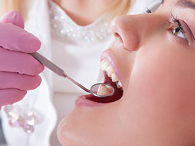 In the image, a dental professional is performing a teeth whitening procedure on a patient s teeth using a light wand.