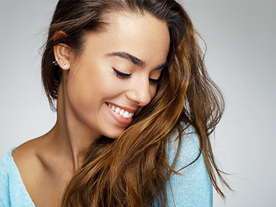 A smiling woman with long hair, wearing a light blue top, against a white background.