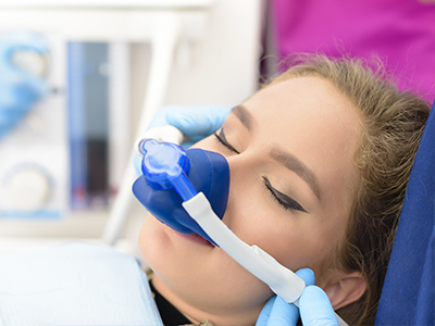 A person receiving medical attention with an oxygen mask attached to their face while lying on a hospital bed.